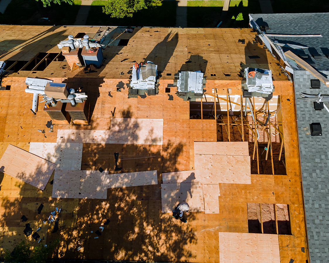 Roof repair, worker with replacing gray asphalt tile shingles on house roofing a construction worker standing on a roof covering